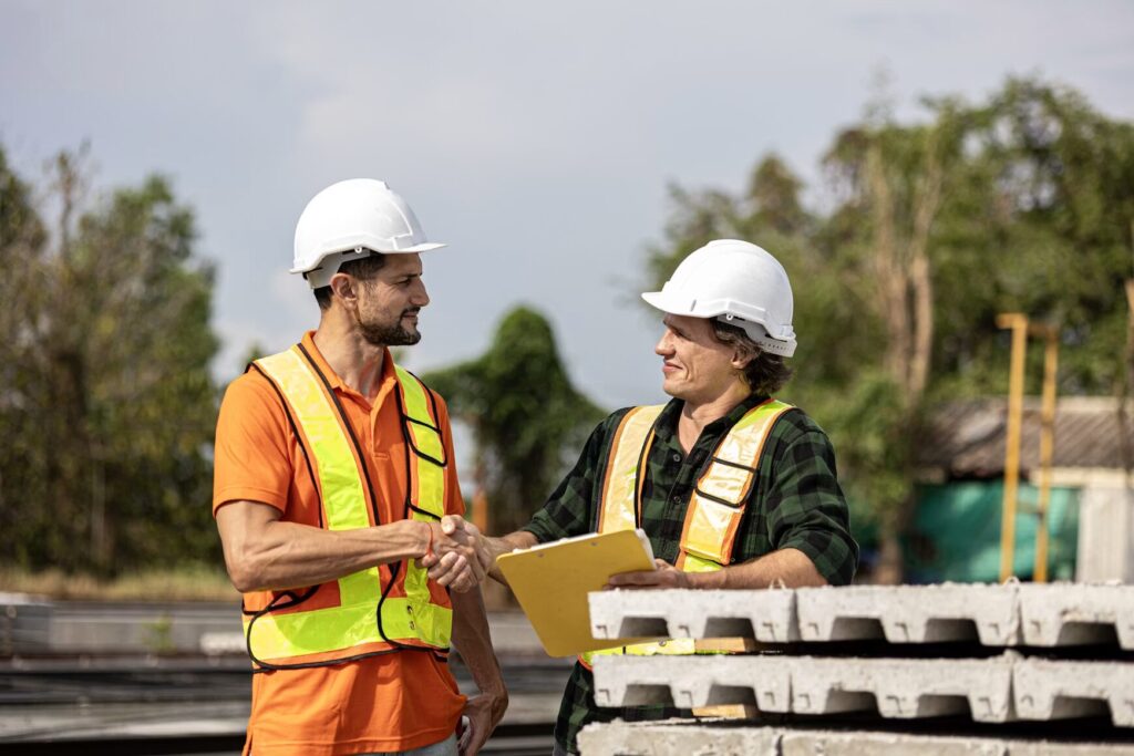 Two construction workers shaking hands on site