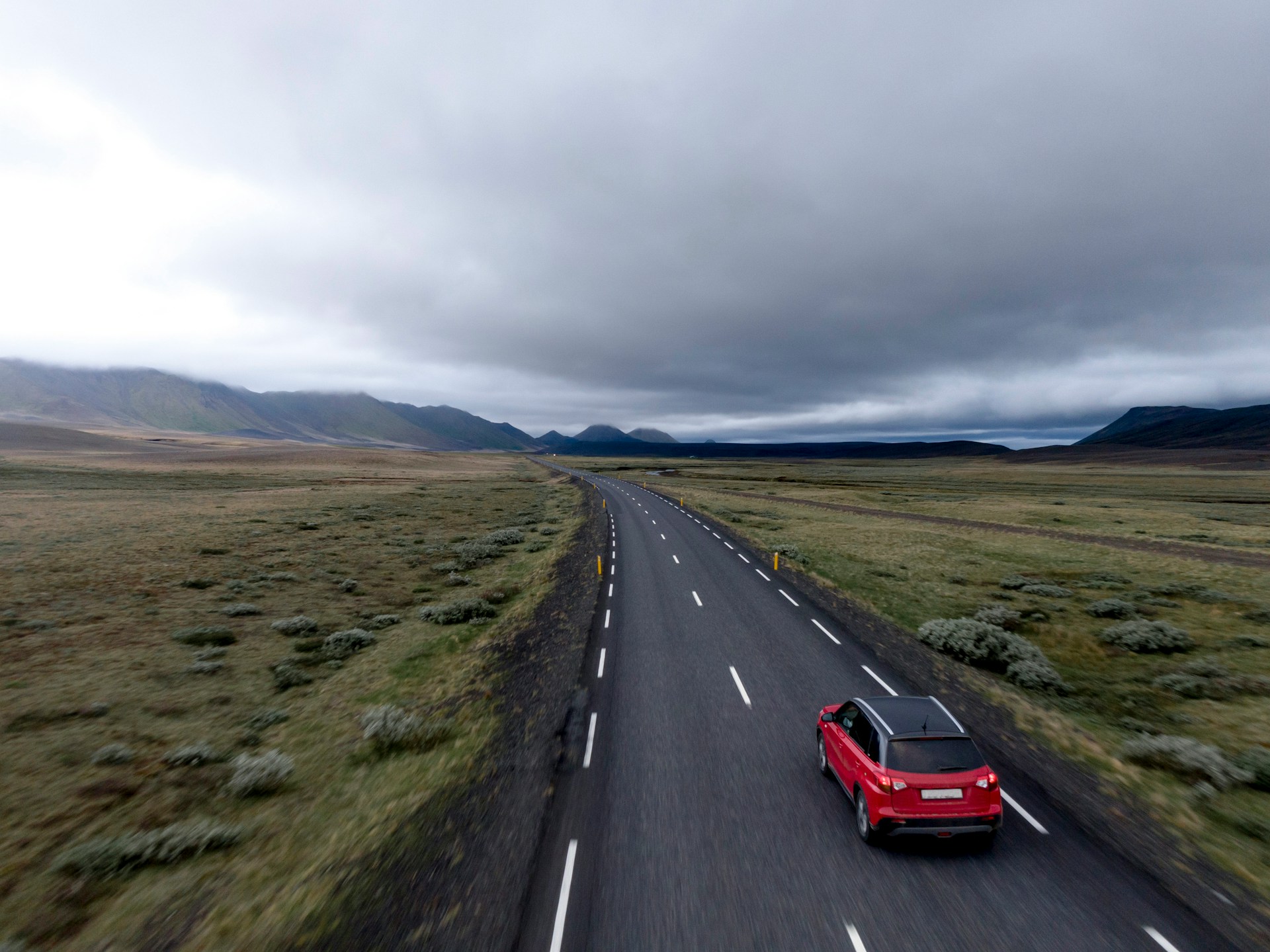 Red car driving on an open road