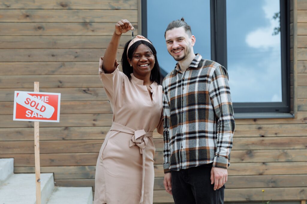 man and woman holding up their key after buying a home