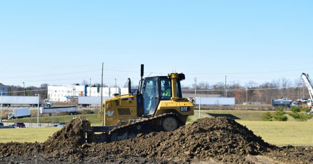 A compact Cat equipment tilling soil in a field.
