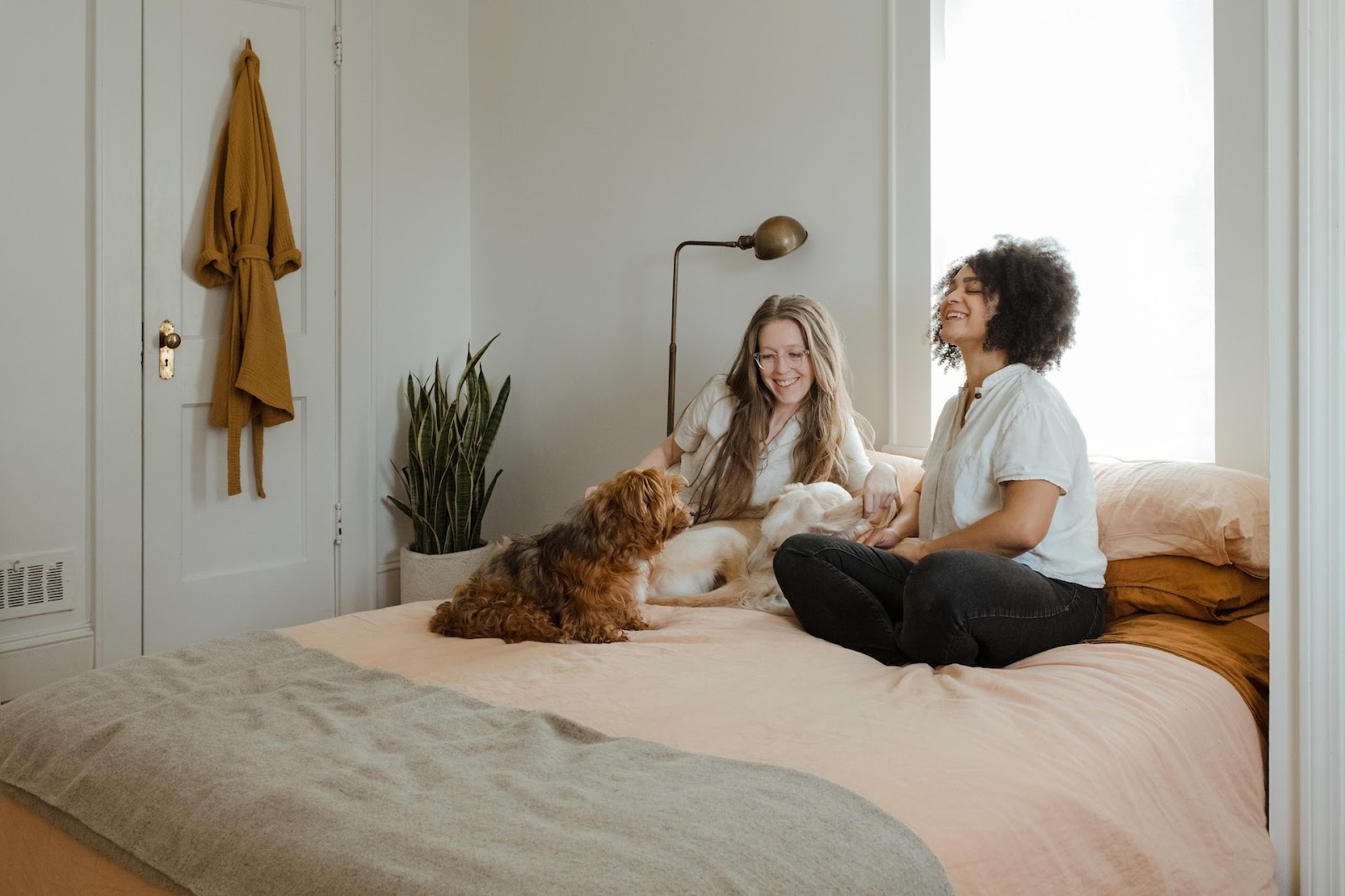 two woman sitting on a bed with a dog