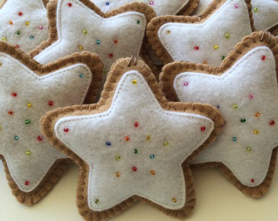 Seven felt cookies with felt icing and bead sprinkles wait to be hung on a Christmas tree.