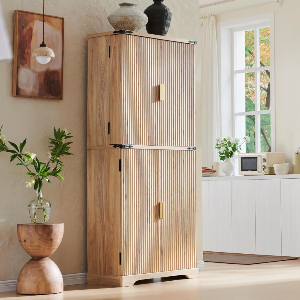 A mid-century fluted kitchen pantry stands against a bare wall. It's a light oak with a noticeable grain pattern. It has two cabinet doors on top and bottom.