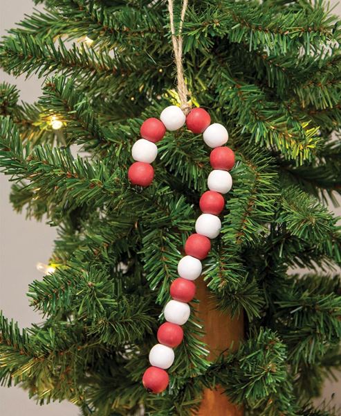 A candy cane made with red and white wooden beads hangs from twine on a mini fake fir Christmas tree.