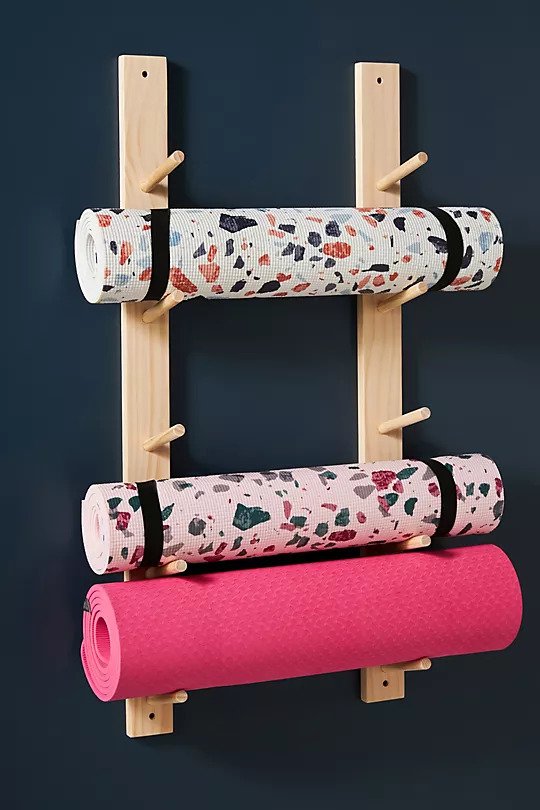 a yoga mat wall organizer with three yoga mats on it