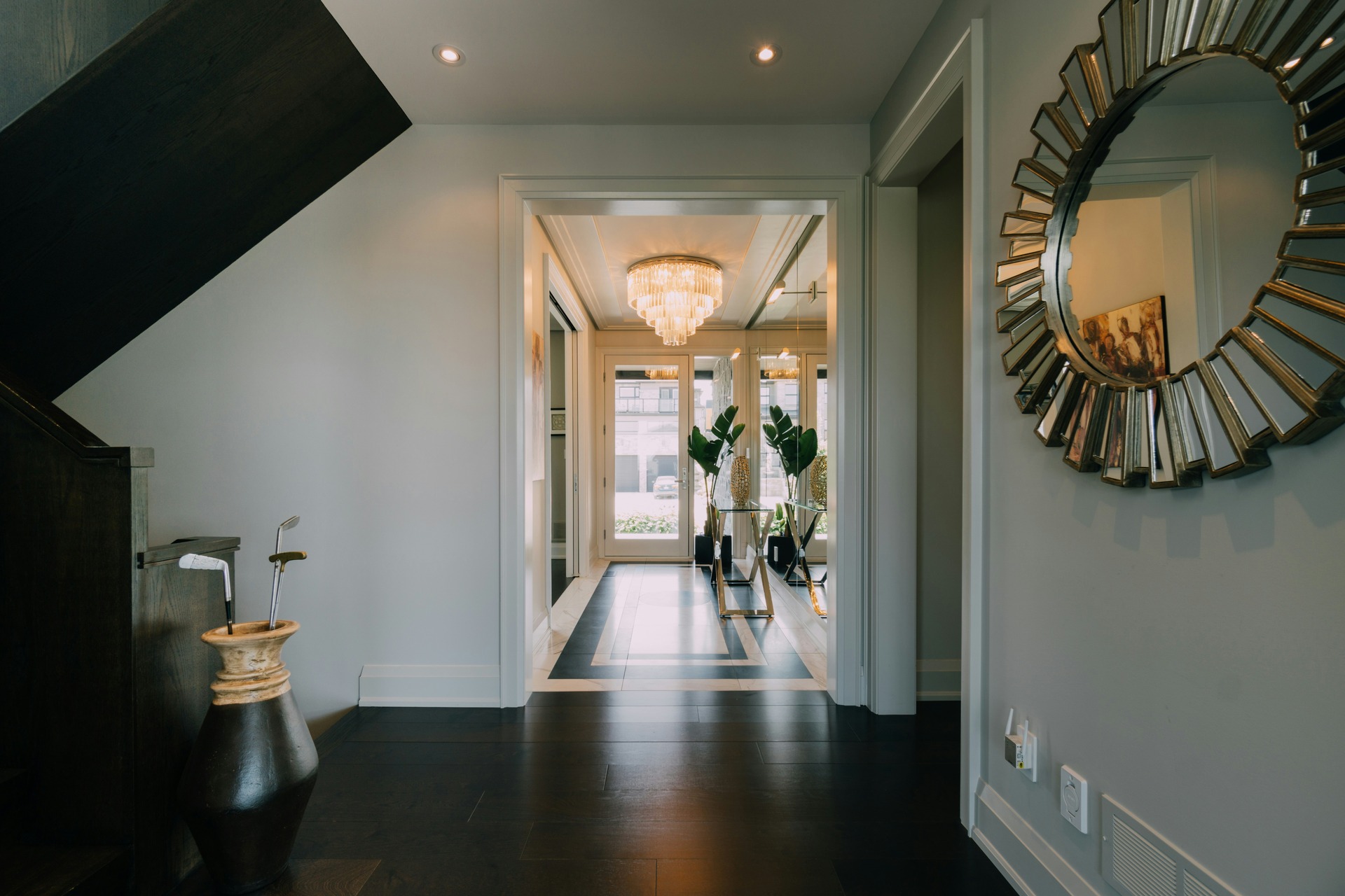 a-hallway-with-a-large-mirror-and-a-chandelier-1-1