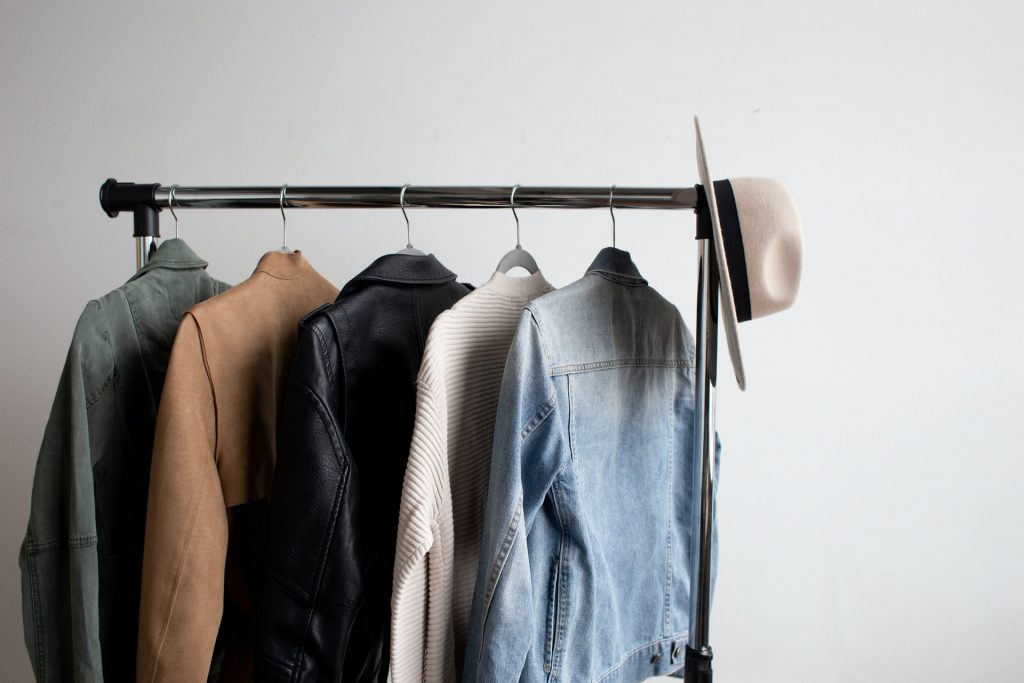 Five jackets and a hat hanging on a black clothing rack