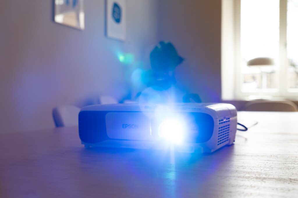 a white Epson projector resting on a table and powered on