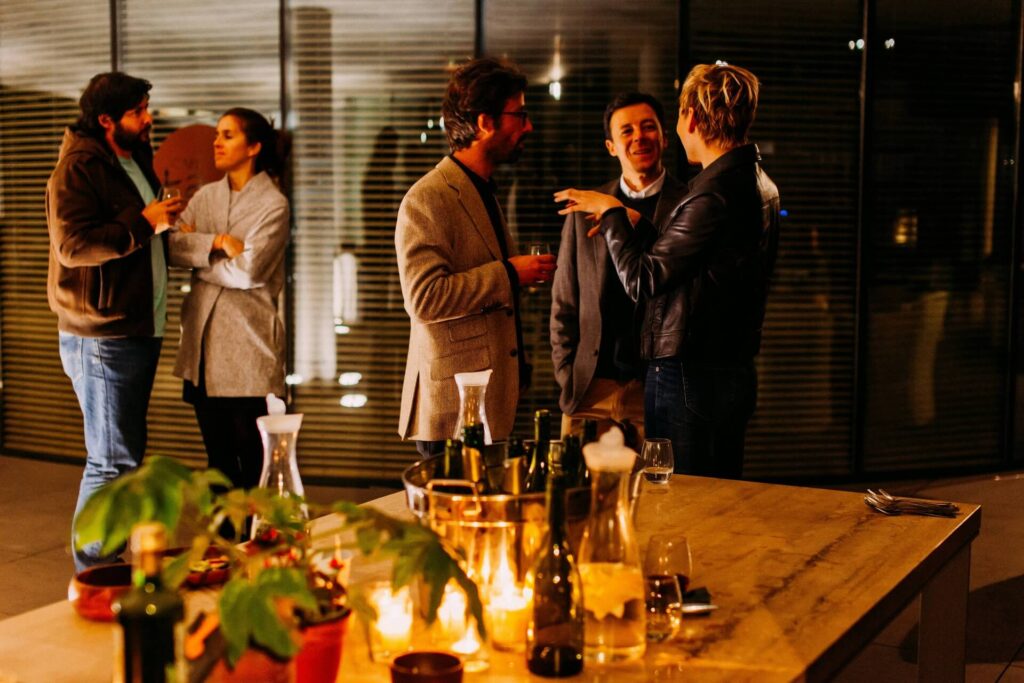 Five people drinking wine and socializing with one another in an intimate gathering.