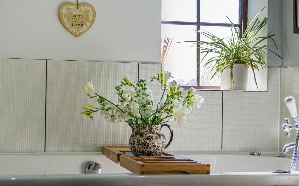white flowers in a pitcher on a bath tray