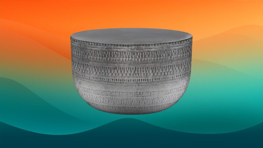 textured dark gray round metal coffee table in front of an orange and teal gradient background
