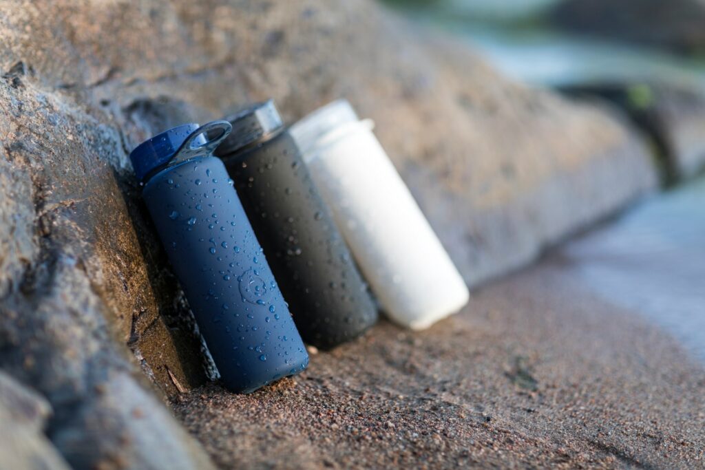 Blue, black and white water containers on brown sand