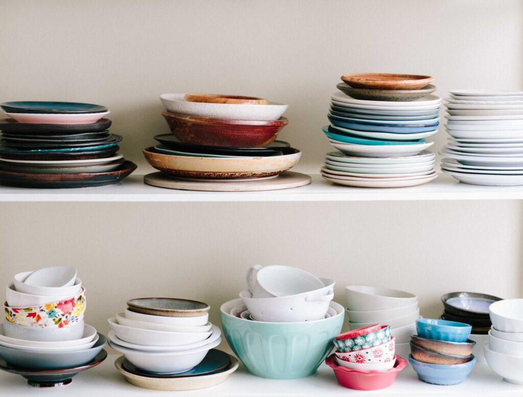 A variety of dishes and bowels on two white shelves