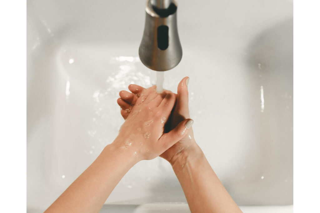 A person washing hands in a sink.