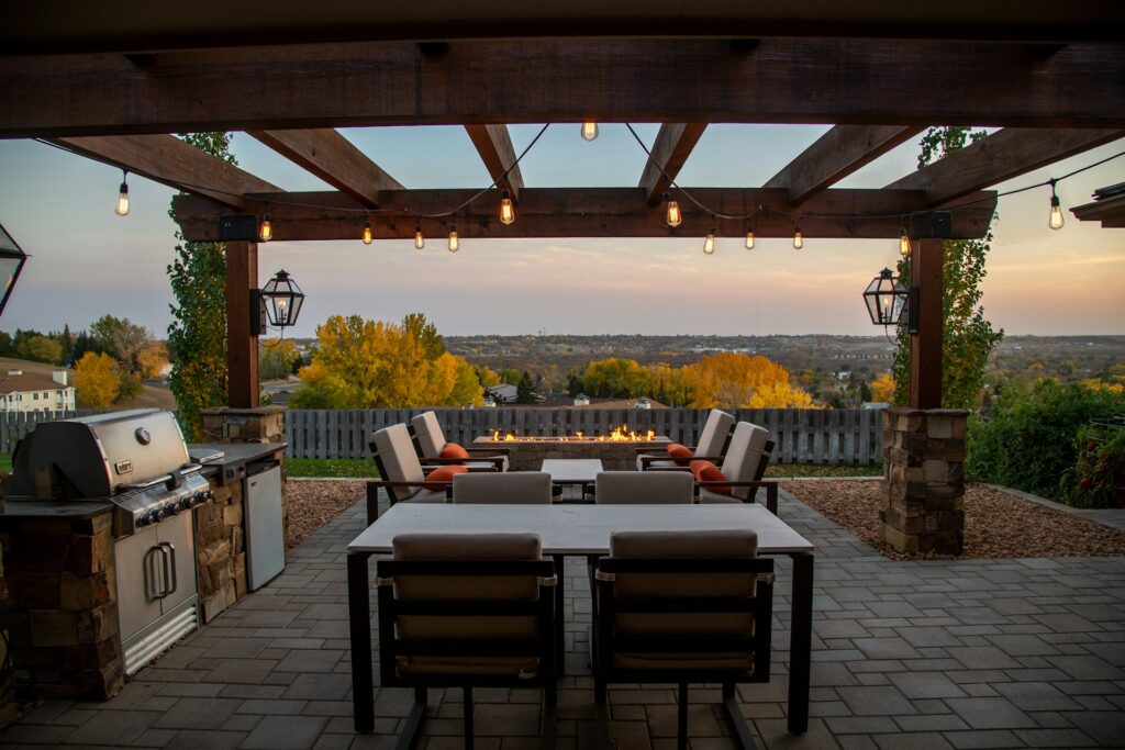 pergola covered patio with table, chairs, and grill