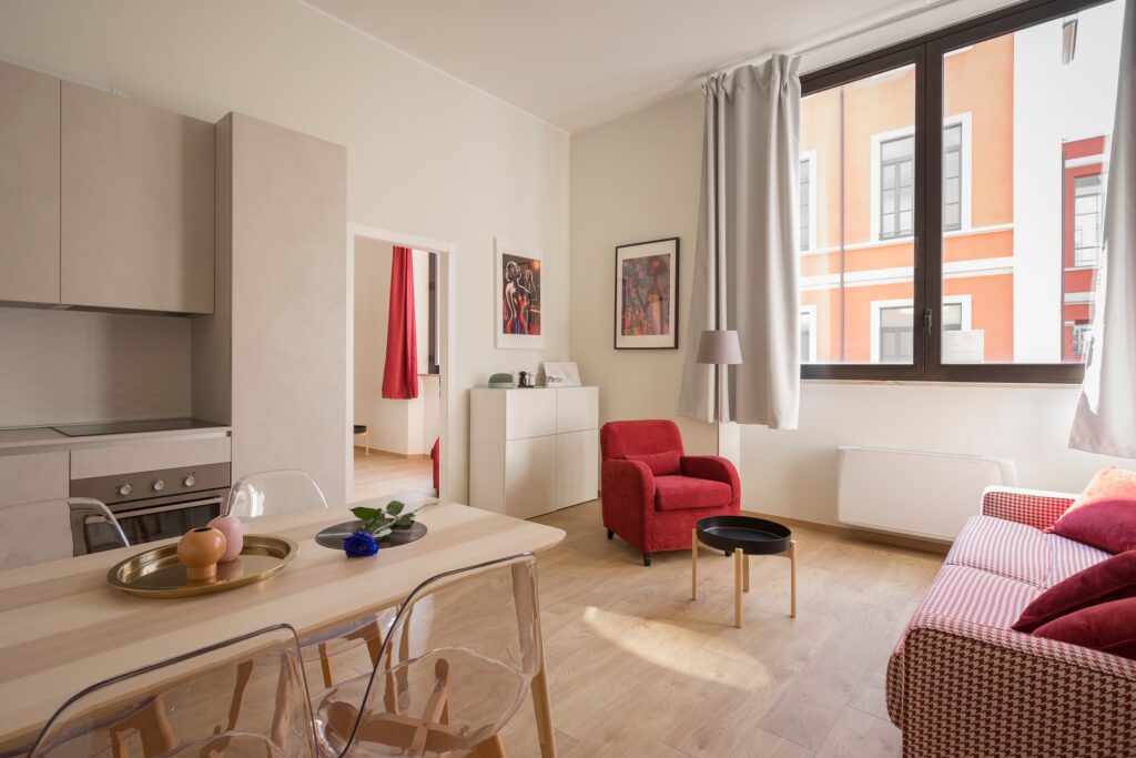 An orderly living room with a red and white couch and a red chair