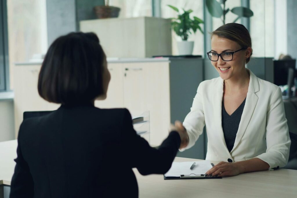 Two women in formal wear shaking hands