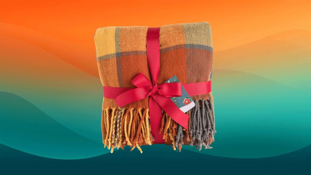 orange, yellow, and red fall decor plaid blanket in front of an orange and teal background