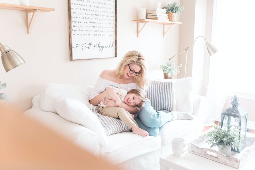 a mother and daughter playing on a couch in a beige living room