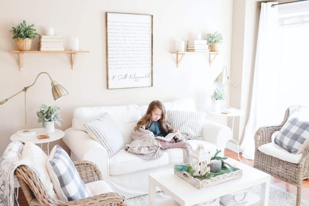 a farmhouse styled room with a girl reading on a white couch