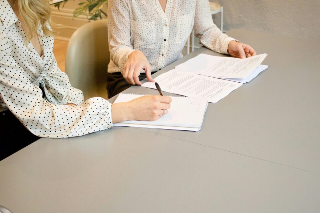 A female licensed real estate agent helping a client sign papers.
