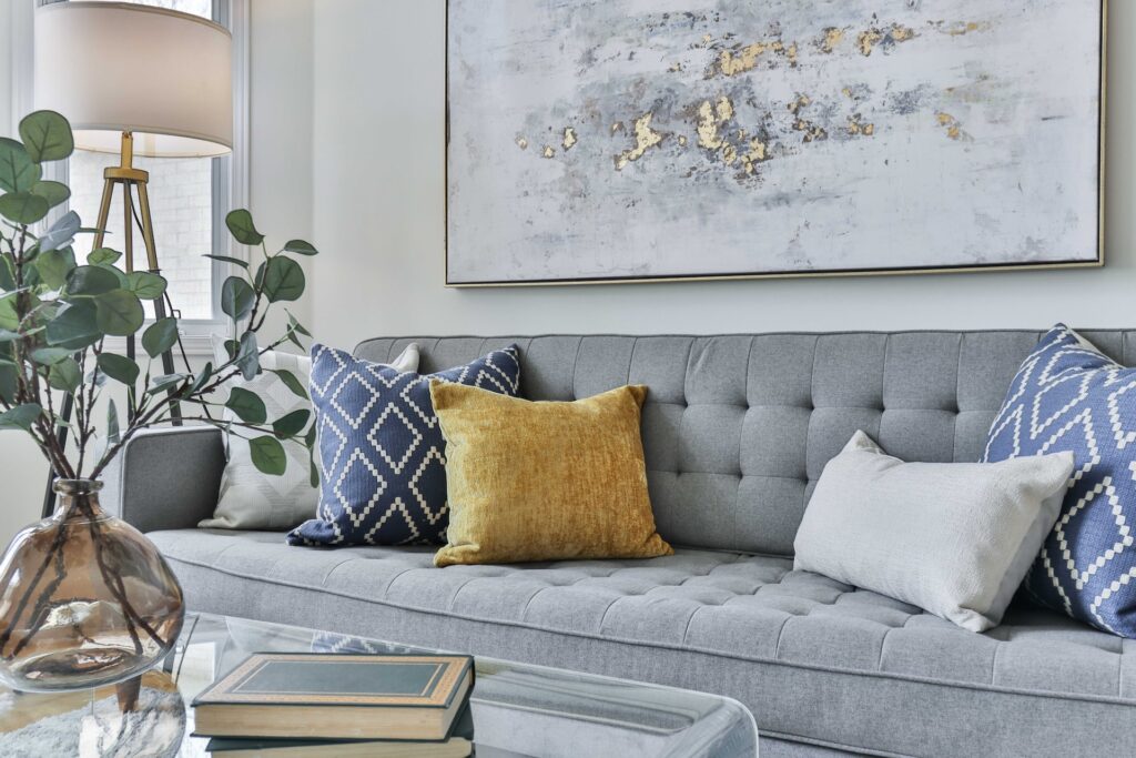 a grey pullout couch with blue and yellow pillows