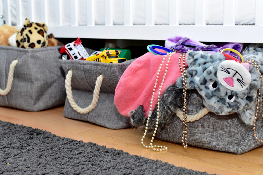Three grey bins with toys stored under a bed for a best organization hack for small spaces