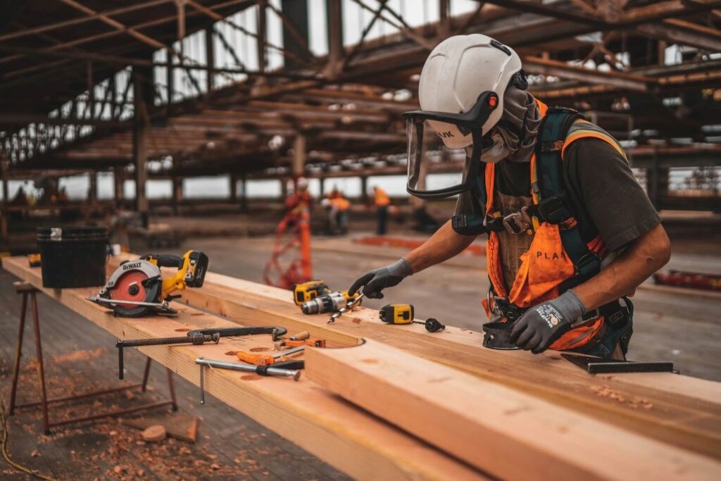 A construction worker using a measuring tape to measure out materials.