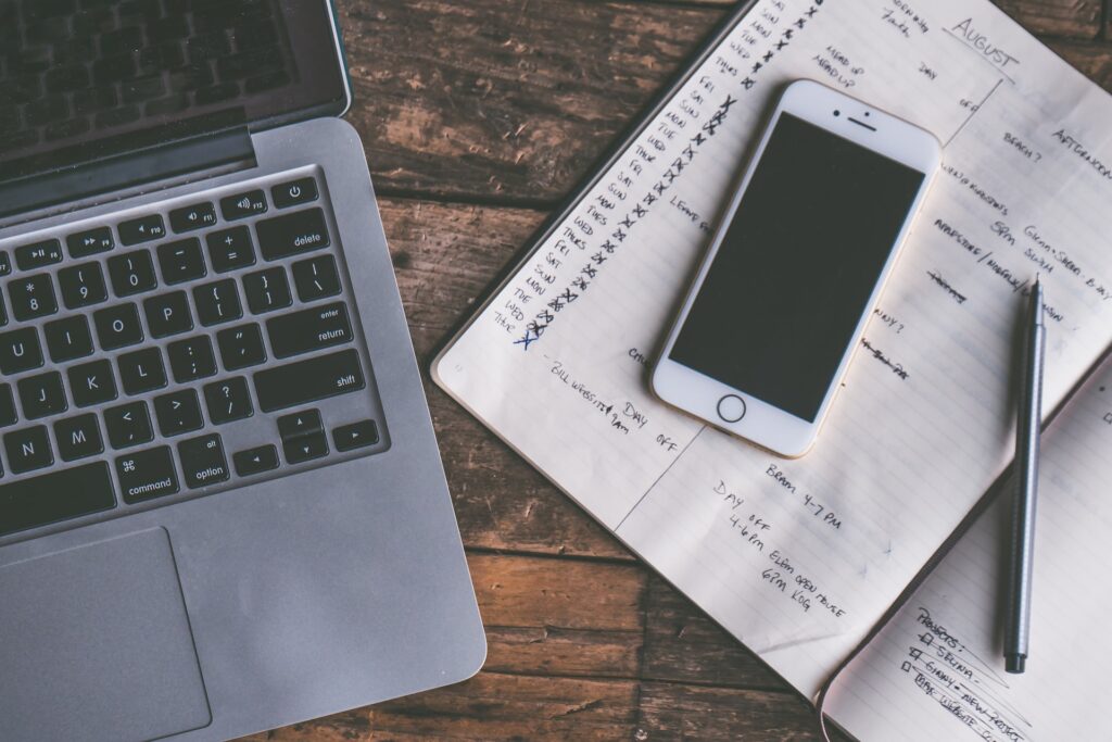 laptop and planner open on a desk with a turned of phone
