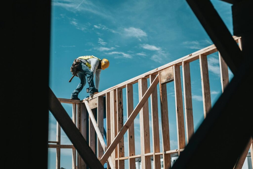 A construction worker standing on wood railings.