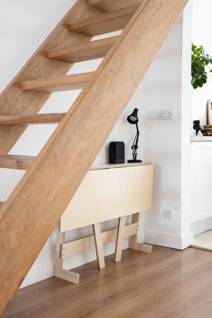 A wooden collapsible standing desk under wooden stairs