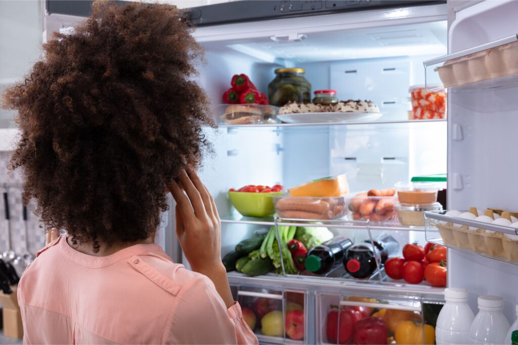 Standing in front of an open fridge filled with fruit