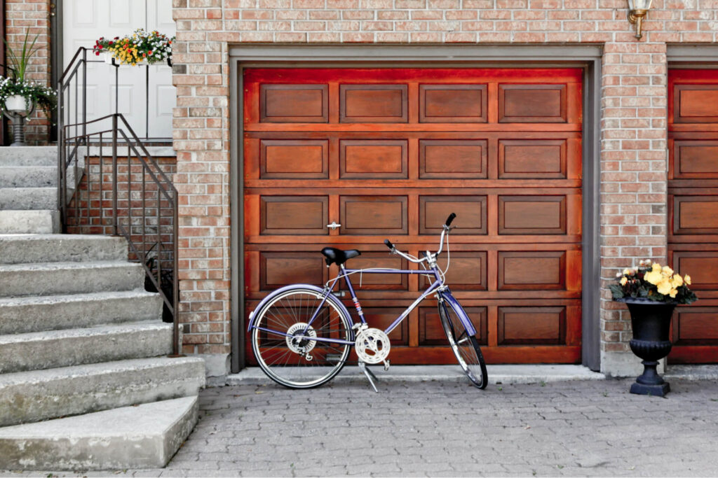 A bike leaning against the exterior of a wooden garage door