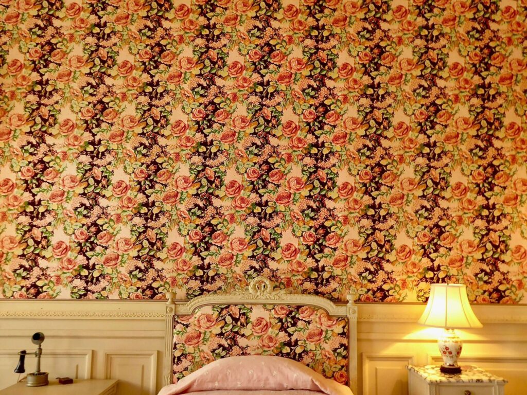 A room filled with wallpaper that matches the headboard of a bed