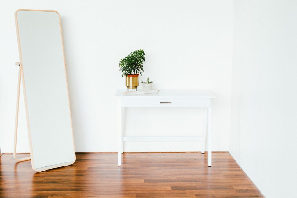 small white table and full length mirror in room