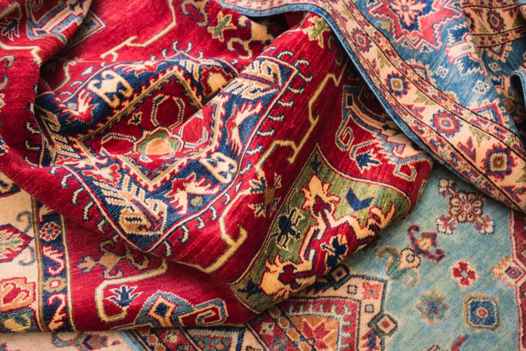 A disheveled red pattered rug with multicolored designs