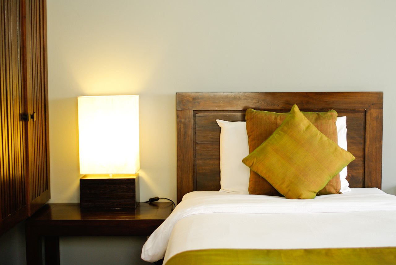 a bedroom with a side table and a bright lamp