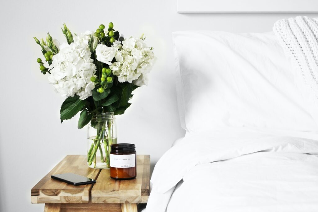 a wooden sidetable near a white bed
