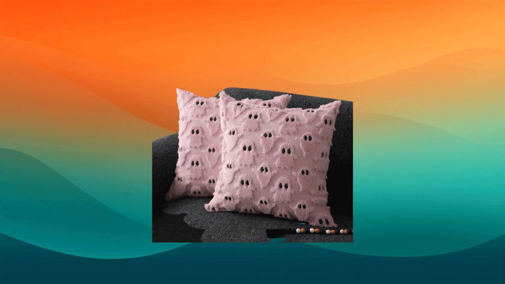 two pink ghost pillows on top of a gray chair in front of an orange and teal background