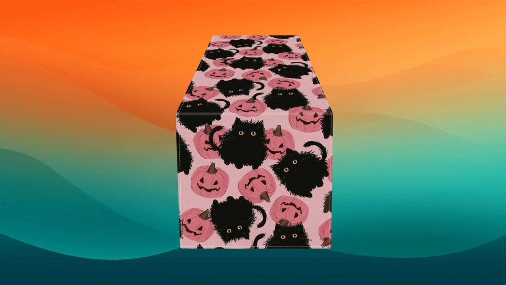 pink pumpkin and black cat table runner in front of an orange and teal background