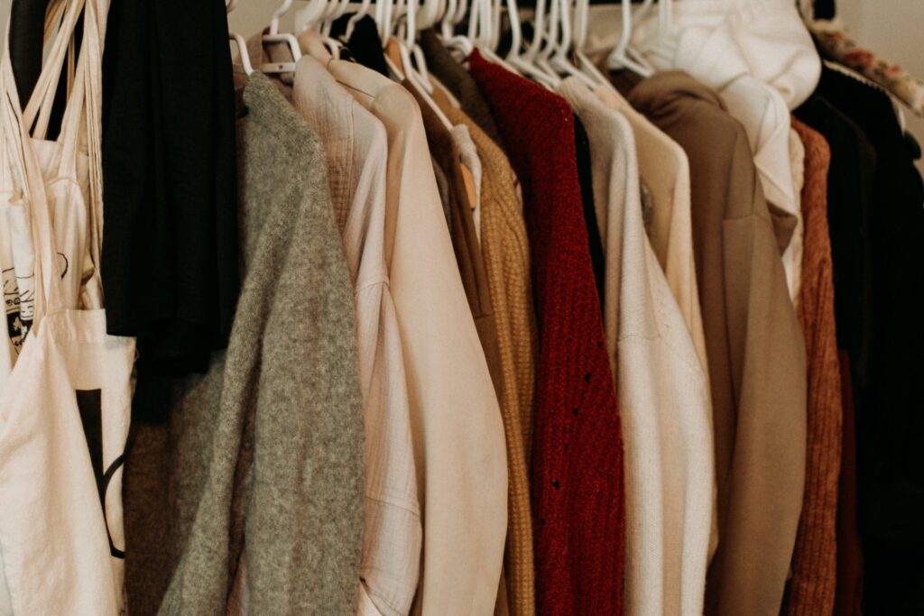 Multiple different colored clothes hanging in a crowded closet