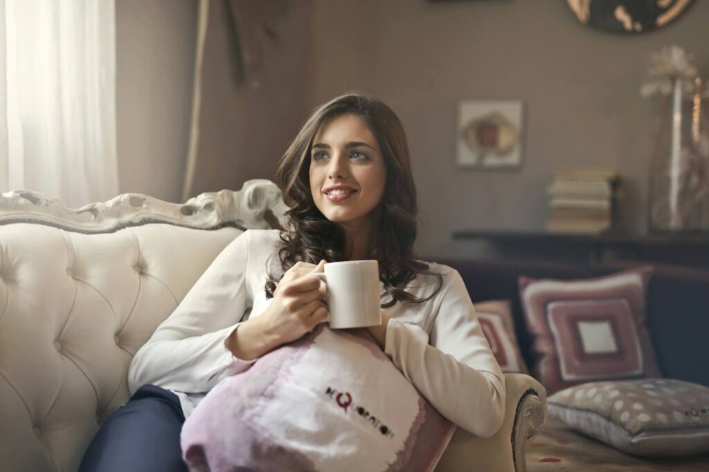 A smiling woman relaxing in a sofa with a drink