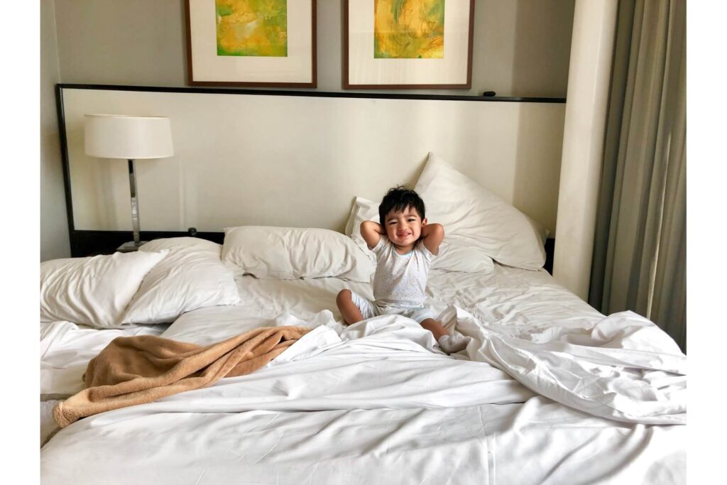Child sitting on a bed wincing