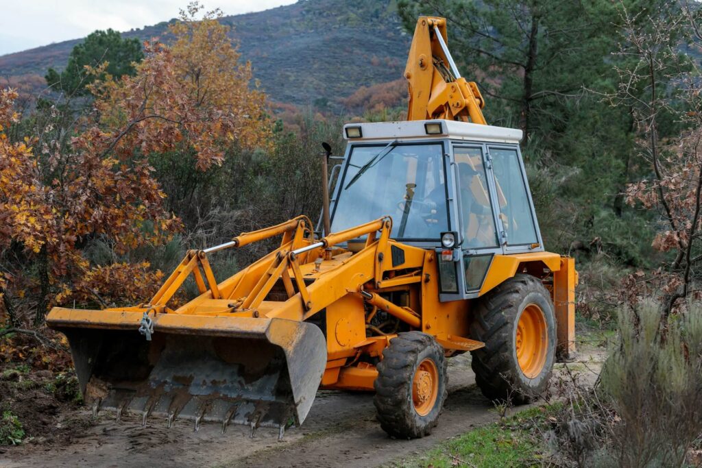 A man operates a tractor on a dirt road