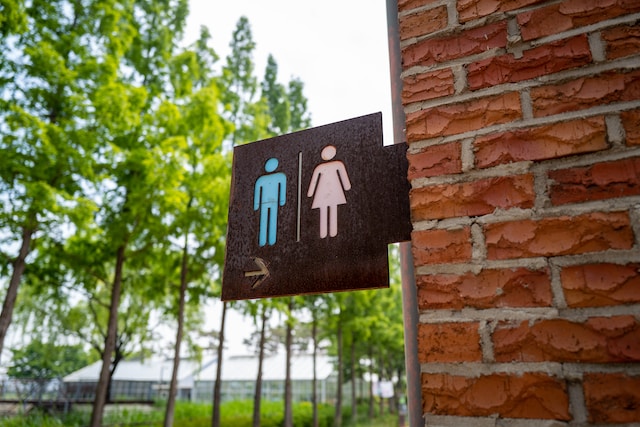 Wooden sign with restroom symbols.