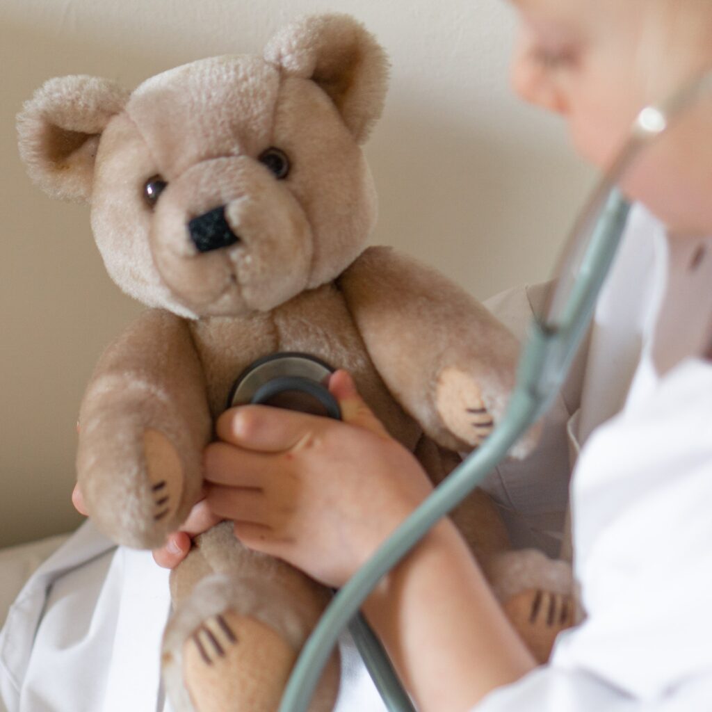 a girl using a stethoscope on a teddy bear