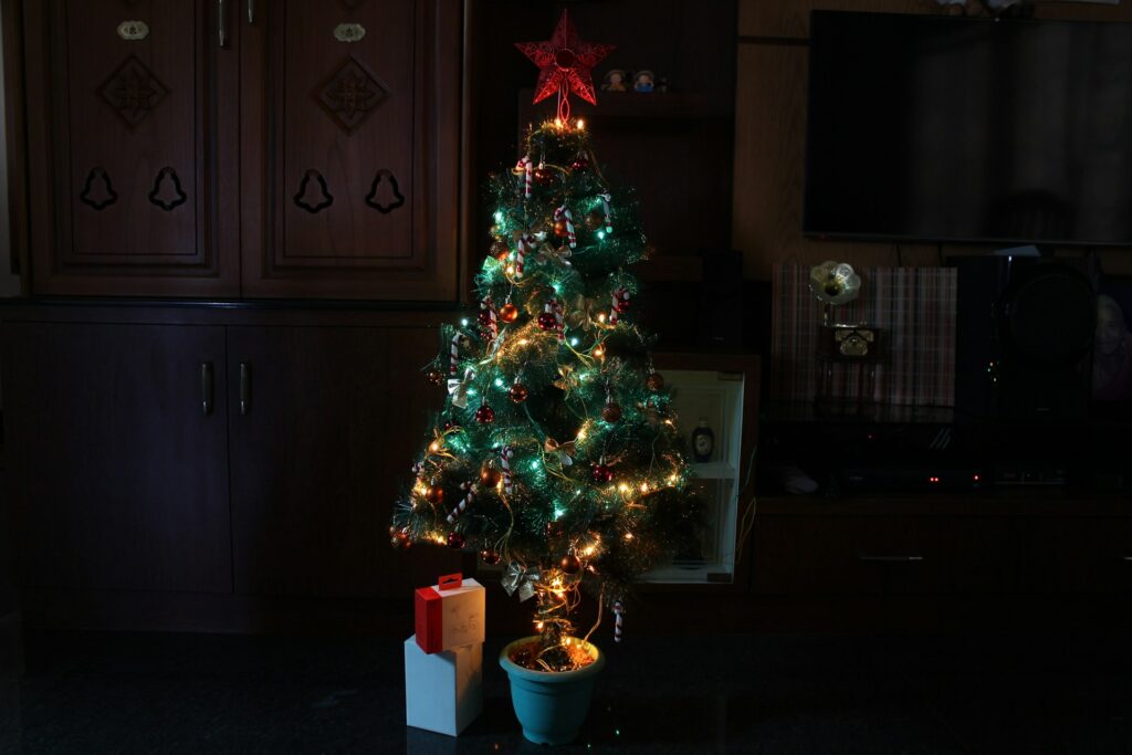 how to put Christmas lights on a tree - a lit tree with gifts below it