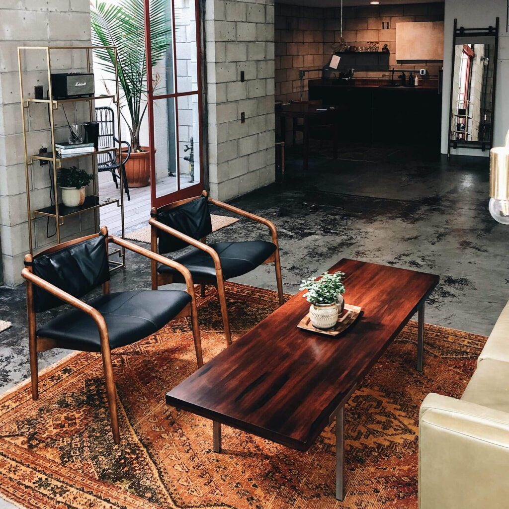 an industrial style living room with two modern chairs and a wooden coffee table