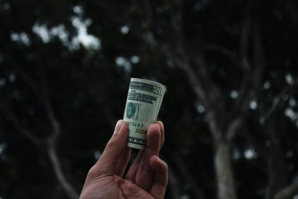 A hand holding a roll of cash