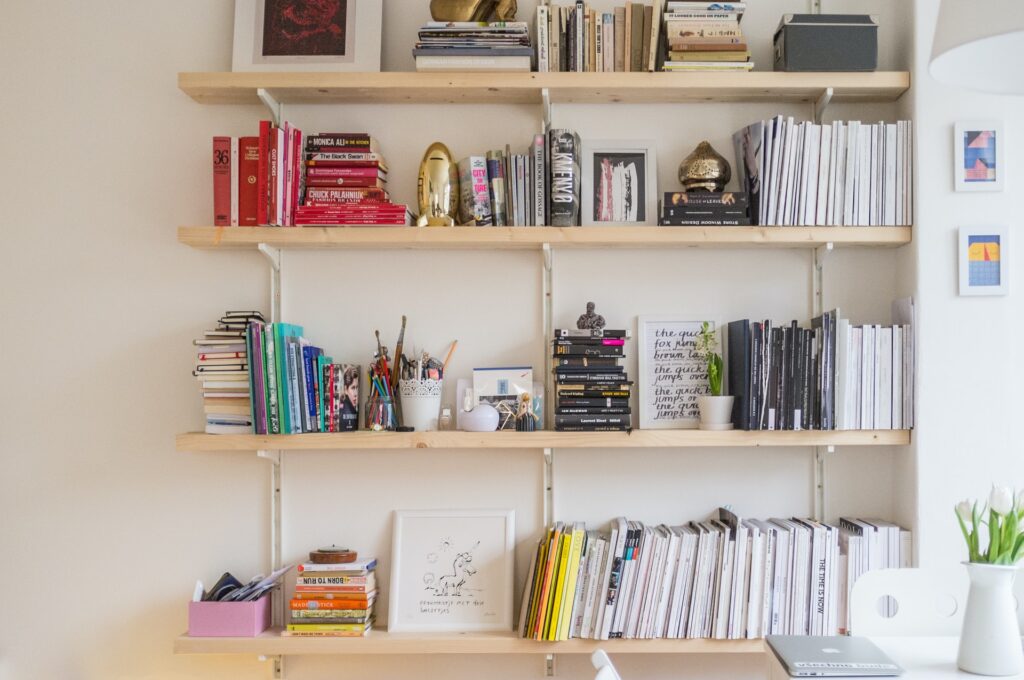 A cluttered shelf with colorful and white books